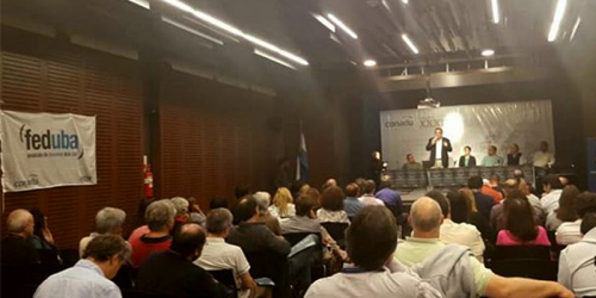 En la imagen vemos decenas de participantes en el congreso y una mesa principal con expositores al fondo